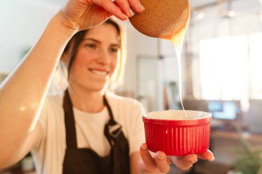 Ev mutfağında karamel yaparken gülümseyen güzel, mutlu pasta şefi kadın.