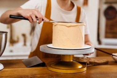 Kafkasyalı pasta şefi kadın sıcak mutfakta kremalı pasta yapıyor.