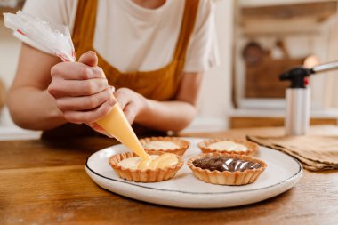 Kafkasyalı pasta şefi kadın sıcak mutfakta kremalı tart yapıyor.