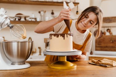 Güzel odaklı pasta şefi kadın sıcak mutfakta çikolatalı kremalı pasta yapıyor.