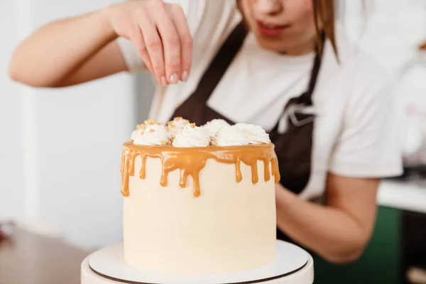 自宅のキッチンでクリームとケーキを作りながら笑顔の美しいパン屋さんの女性 — ストック写真