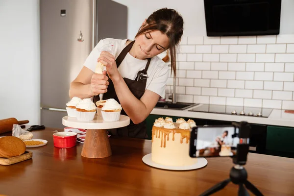 カメラ映像の焦点を当てたパン屋の女性作るケーキでクリームでキッチン — ストック写真