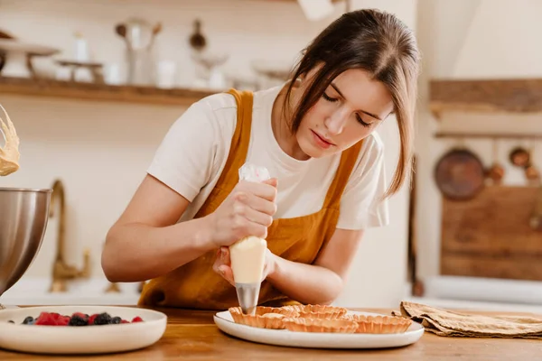 美しい濃縮ペストリーシェフ女性作るタルトとともにクリームで居心地の良いキッチン — ストック写真