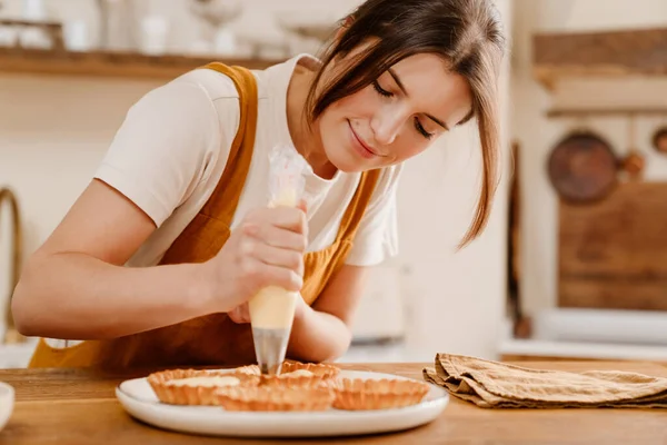 Piękny Szczęśliwy Cukiernik Kobieta Uśmiecha Się Robiąc Ciasta Śmietaną Przytulnej — Zdjęcie stockowe