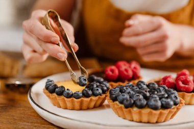 Kafkasyalı pasta şefi kadın sıcak mutfakta çilekli tart yapıyor.