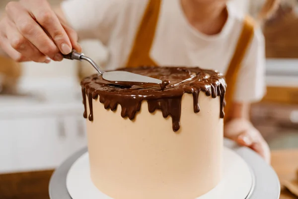 コーカシアのペストリーシェフの女性は屋内でチョコレートクリームとケーキを作る — ストック写真