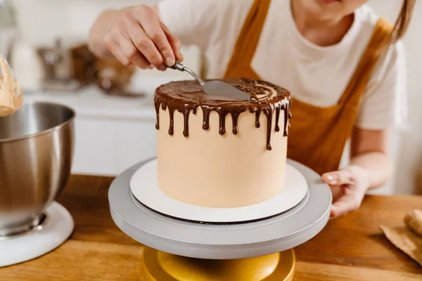 コーカシアのペストリーシェフの女性は屋内でチョコレートクリームとケーキを作る — ストック写真