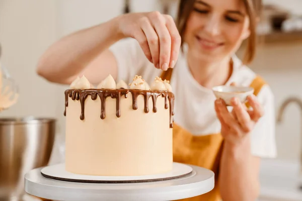 居心地の良いキッチンでクリームとケーキを作りながら笑顔の美しい幸せなペストリーシェフの女性 — ストック写真