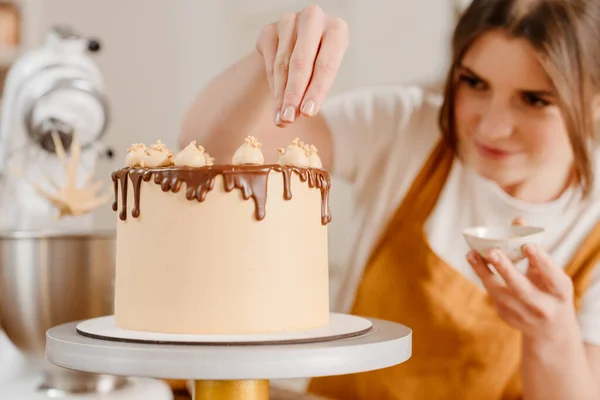 美しい焦点を当てたペストリーシェフの女性は居心地の良いキッチンでチョコレートクリームとケーキを作る — ストック写真