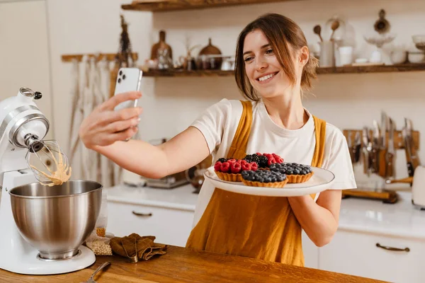 Gyönyörű Mosolygós Cukrász Csinál Szelfi Torták Mobiltelefon Kényelmes Konyha — Stock Fotó