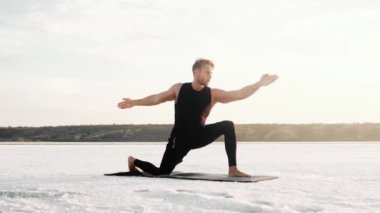 A focused young athlete is doing yoga outside on the yoga mat