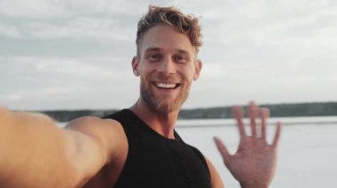 A smile young sportsman is recording a selfie video standing outside