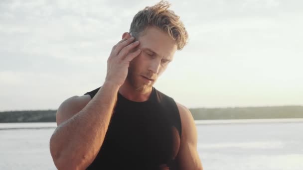 Pleased Young Man Putting His Earbuds Standing — Αρχείο Βίντεο