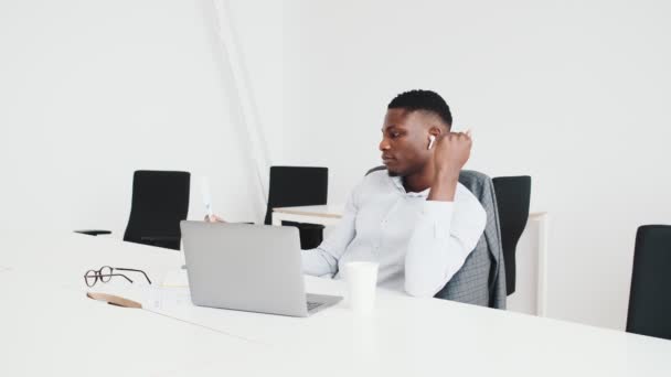 Negro Positivo Con Auriculares Está Usando Teléfono Inteligente Mientras Trabaja — Vídeos de Stock