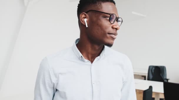 成功したアフリカのビジネスマンが眼鏡をかけてオフィスに立っているカメラを見ている — ストック動画