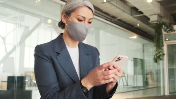 Focused Elder Businesswoman Wearing Facial Protected Mask Using Her Smartphone — Vídeo de Stock