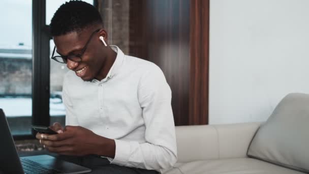 Smiling African American Businessman Wearing Earbuds Using His Cell Phone — Stockvideo