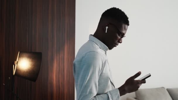 Boční Pohled Pohledného Afrického Podnikatele Bezdrátových Sluchátkách Používá Svůj Smartphone — Stock video