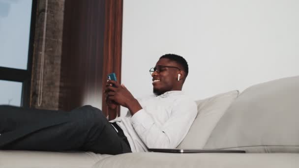Hombre Afroamericano Feliz Con Auriculares Inalámbricos Está Usando Teléfono Inteligente — Vídeo de stock