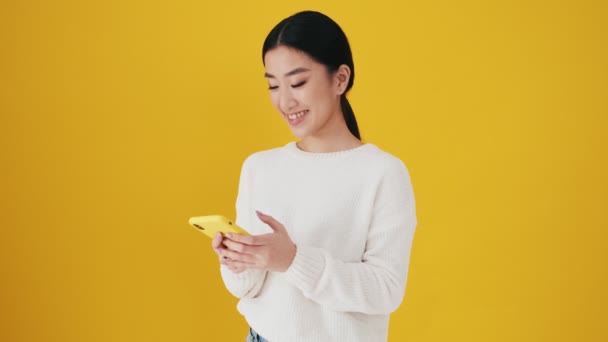 Pozitif Asyalı Bir Kadın Atölyedeki Sarı Duvarda Duran Akıllı Telefonunu — Stok video