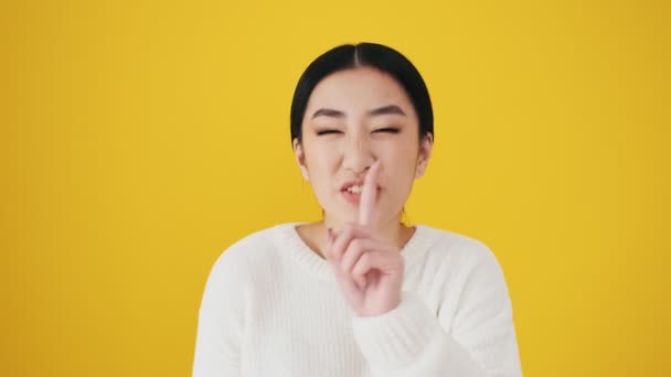 Smiling Asian Woman Showing Secret Gesture Standing Isolated Yellow Wall — Stock Video