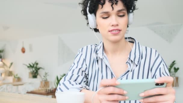 Een Gefocuste Vrouw Met Een Koptelefoon Gebruikt Haar Smartphone Terwijl — Stockvideo