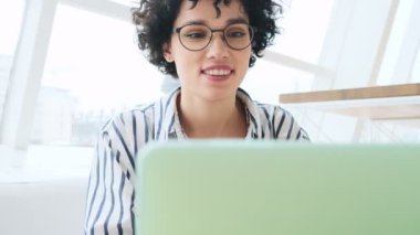 Memnun bir kadının yakın plan görüntüsü kafede oturan dizüstü bilgisayarını kullanıyor.