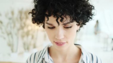 Gülümseyen bir kadın apartmandaki kameraya bakıyor.