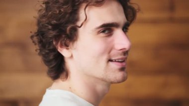 The side-view of happy man turning to camera with smile while standing in the wooden studio