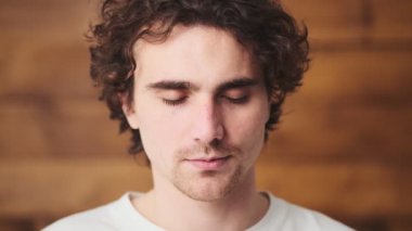 The portrait of curly-haired man with closed eyes laughing and then looking at the camera