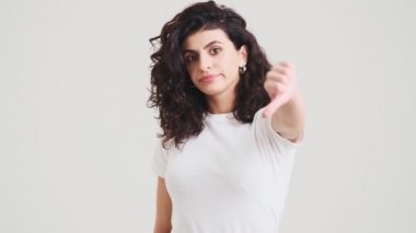 The upset woman showing thumb-down to the camera while standing in the studio