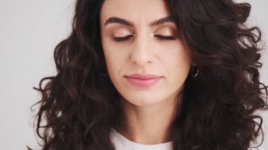 The close-up view of a smiling woman's face blowing kisses to the camera