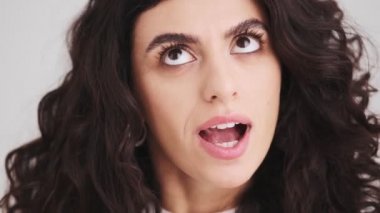 The close-up view of the face of a thoughtful woman thinking over something while looking around