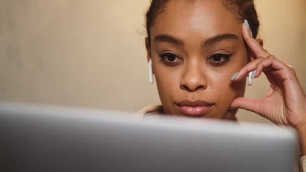 坐在笔记本电脑前 头戴耳机看书的黑人妇女的近照 — 图库视频影像