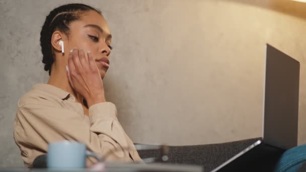 在笔记本电脑键盘上打字时戴耳机的黑人妇女的侧视图 — 图库视频影像