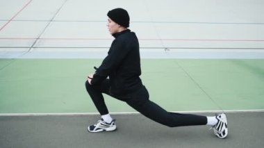 Sağlıklı genç bir sporcu, stadyumda bacaklarını açarken maraton koşmadan önce hazırlanıyor.