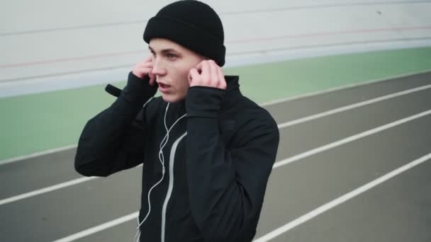 Egy Erős Fiatal Sportoló Aki Fekete Sportruhát Visel Felveszi Fülhallgatóját — Stock videók