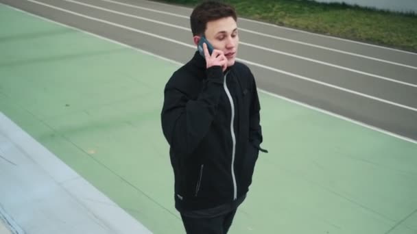 Beau Jeune Athlète Parle Sur Son Smartphone Tout Marchant Stade — Video
