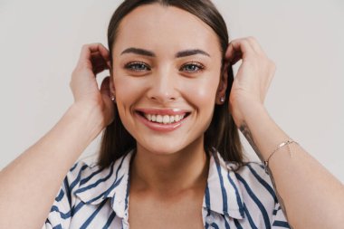 Mutlu güzel esmer kız gülümsüyor ve beyaz arka planda izole edilmiş kameraya bakıyor.