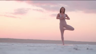 Memnun bir sarışın kadın yoga egzersizleri yapıyor. Sabahları tek ayağının üzerinde duruyor.