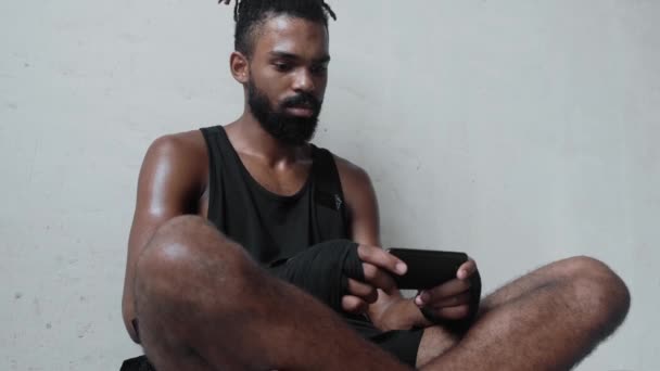 Calm Young Afro American Sportsman Using His Smartphone Sitting Wall — Vídeo de Stock