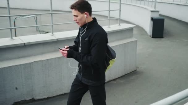 Een Glimlachende Jonge Sportman Luistert Naar Muziek Tijdens Het Lopen — Stockvideo