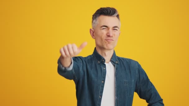 Mature Disgruntled Man Showing Thumb Gesture Camera While Standing Yellow — Stockvideo