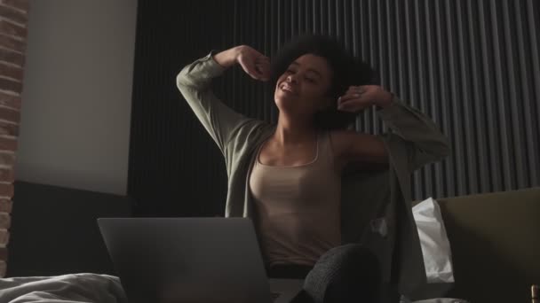 部屋に座っている間 黒の女性がストレッチと彼女の足にノートパソコンを保持 — ストック動画
