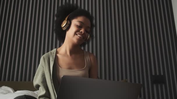 Черная Счастливая Женщина Слушает Музыку Наушниках Держит Ноутбук Ногах Сидя — стоковое видео