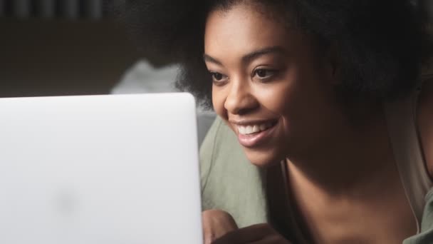 一位黑人妇女坐在明亮的房间里 看着笔记本电脑 微笑着在键盘上输入答案 — 图库视频影像