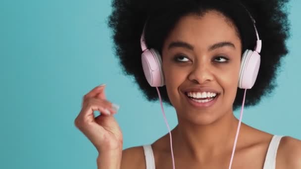 スタジオでヘッドフォンを着用し 指をスナップ幸せな黒人女性の顔のクローズアップショット — ストック動画