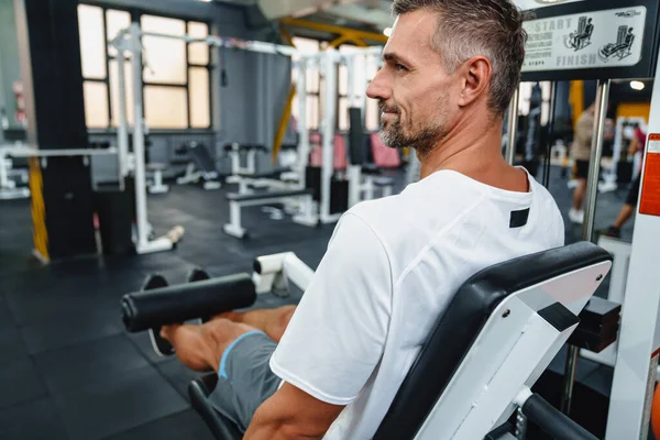 Attraente Uomo Sportivo Sano Fiducioso Utilizzando Seduto Macchina Arricciacapelli Gamba — Foto Stock