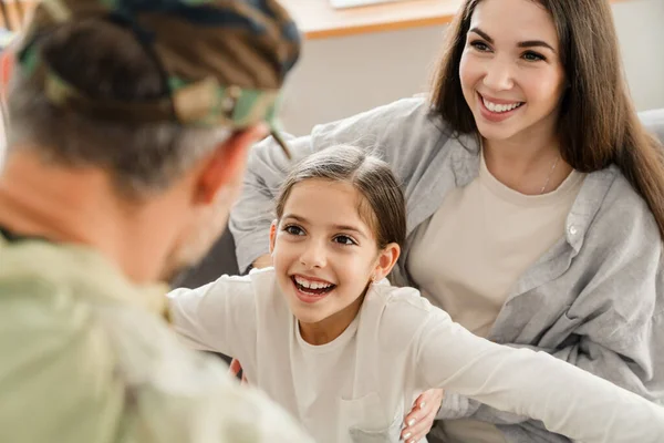 Happy kids and their mom meeting military dad in uniform indoors. Family reunion or returning home concept