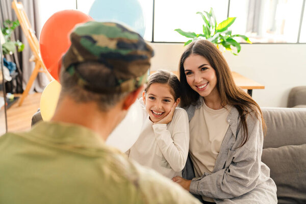 Happy kids and their mom meeting military dad in uniform indoors. Family reunion or returning home concept